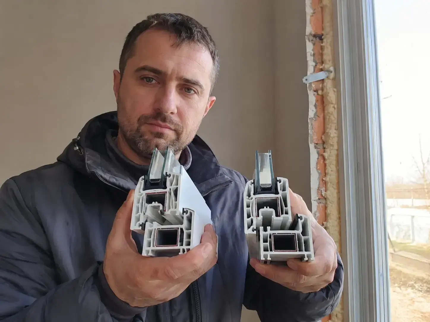 Instalater prikazuje prerez PVC profila sa vidljivim komorama pored otvorenog prozora