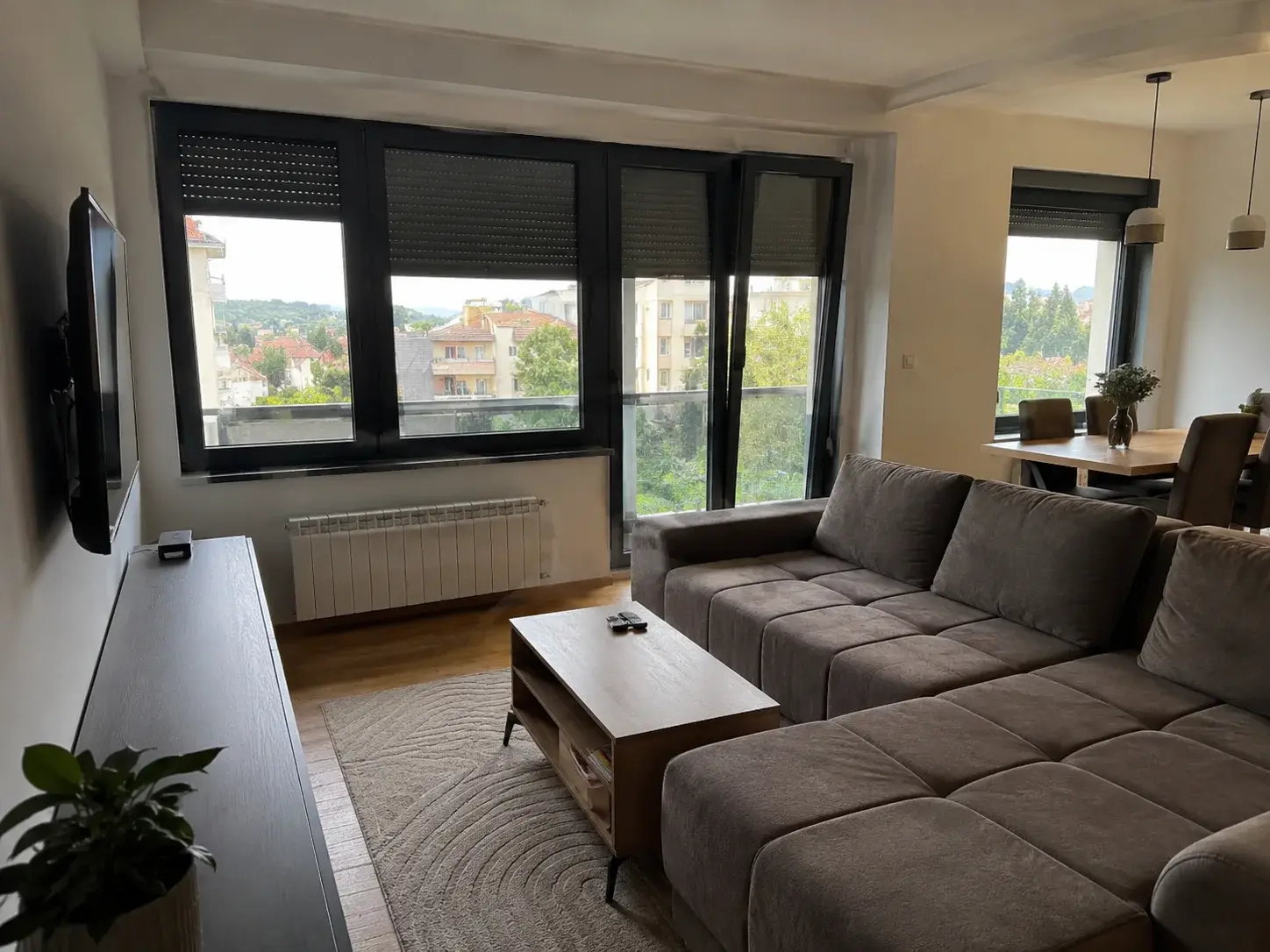 Unutrašnji enterijer moderne kuće sa velikim antracit prozorima, prirodno svetlo, neutralne boje zidova.