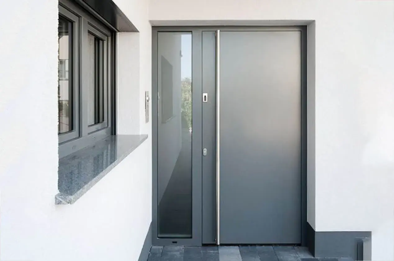 Siva ulazna vrata sa vertikalnom inox ručkom na ulazu porodične kuće u Novom Sadu