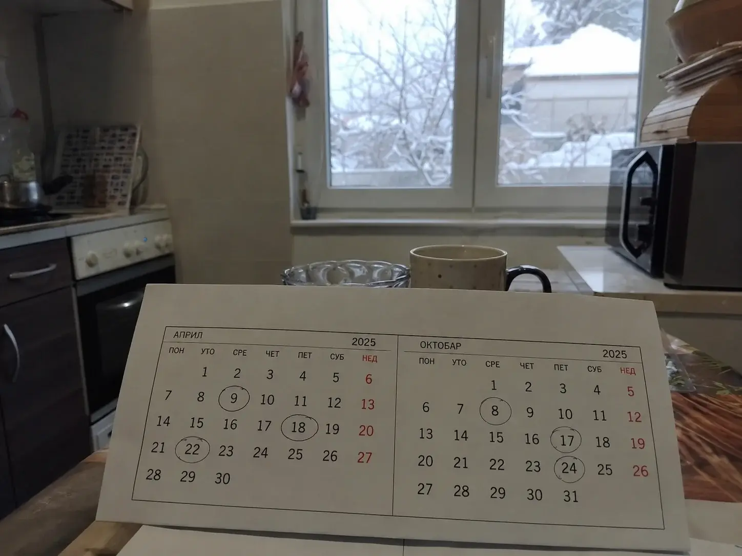 Kalendar sa zaokruženim datumima u proleće i jesen, prozor sa zimskim pogledom u pozadini.