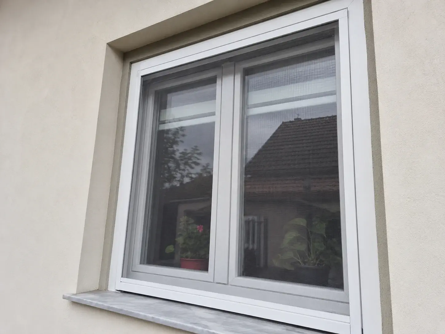 Fiksni komarnik sa belim aluminijumskim ramom na PVC prozoru porodične kuće